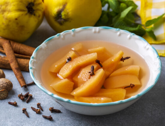 Imagine de aproape cu felii de gutui scufundate în sirop de gutui într-un bol alb