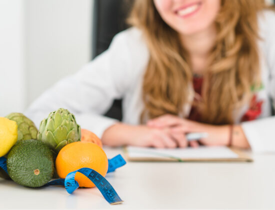 tanara fericita care sta la masa, portii de fructe si legume cantarite