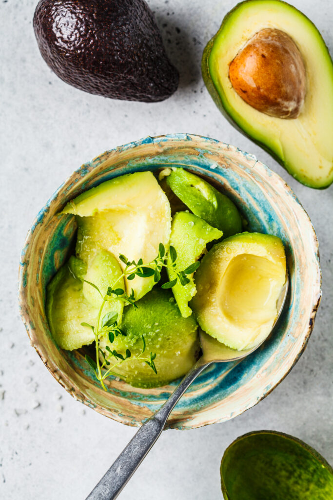 Bol cu bucăți de avocado. Lângă, încă 2 jumătăți de avocado