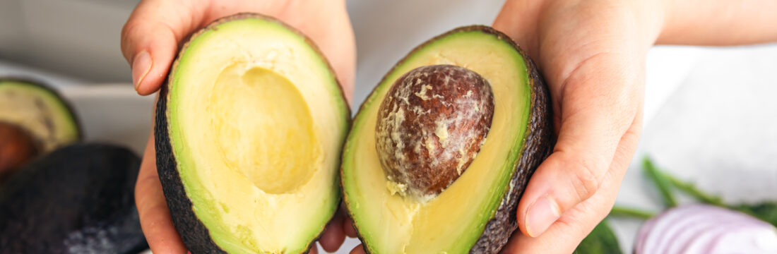 Persoană care ține 2 jumătăți de avocado în mână