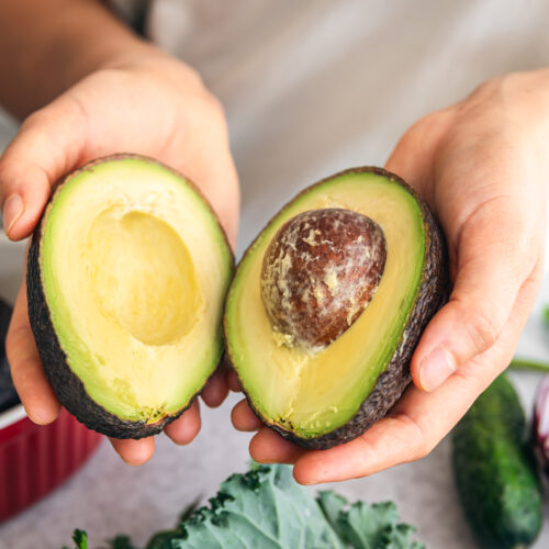 Persoană care ține 2 jumătăți de avocado în mână