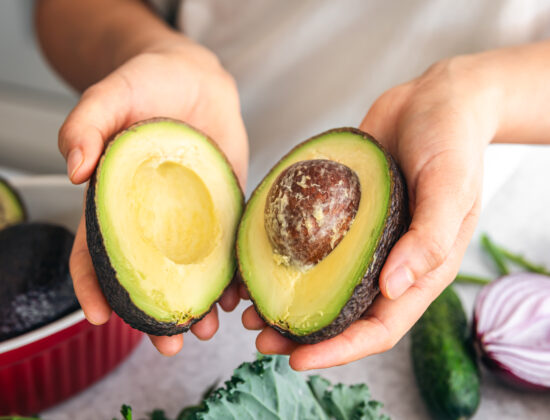 Persoană care ține 2 jumătăți de avocado în mână