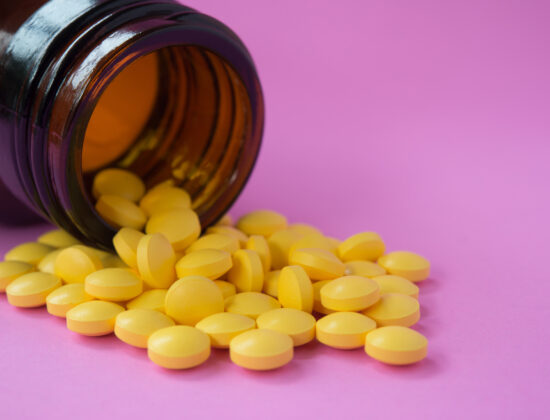 Berberină în format de supliment. Pastile galbene care se revarsă dintr-un flacon, pe un fundal mov. Imagine de aproape