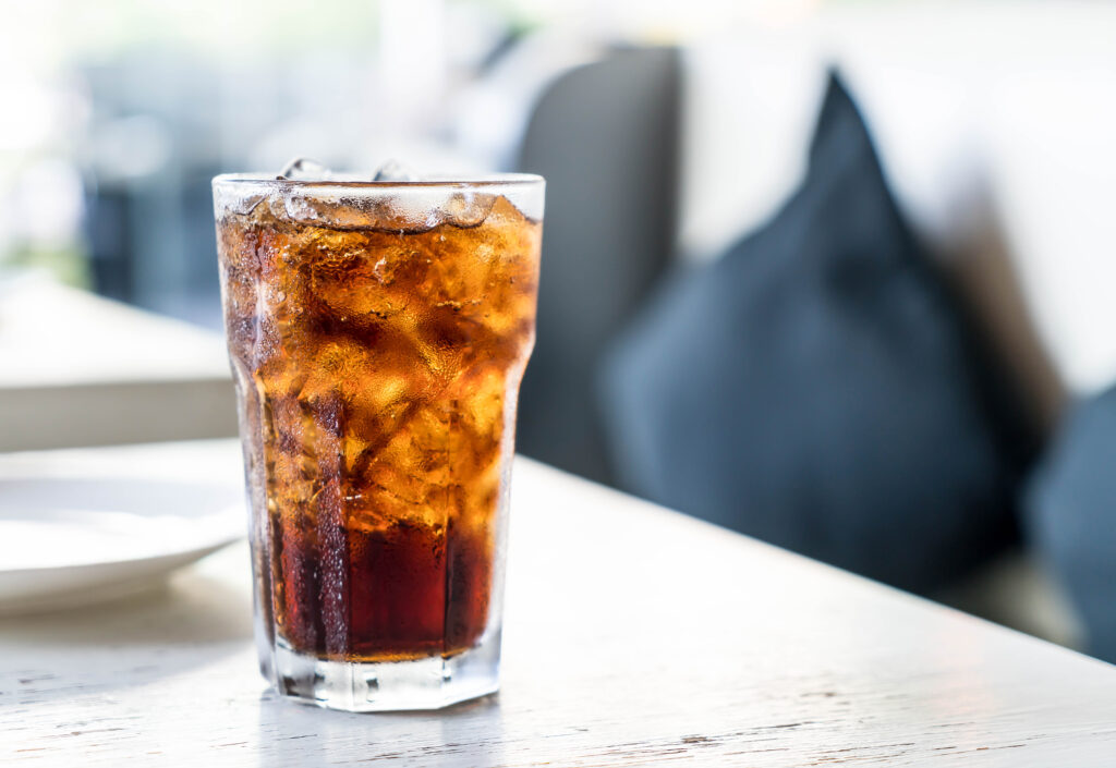un pahar de cola cu cuburi de gheata 