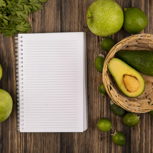 avocado si mere verzi pe masa, langa o agenda goala