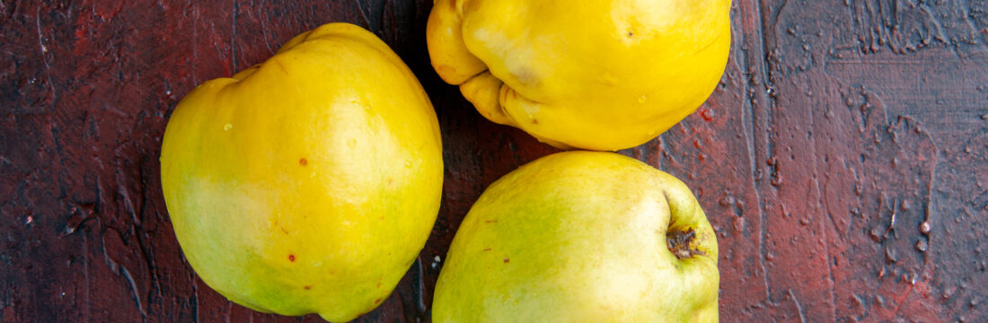 trei gutui delicioase pe masa, fundal închis la culoare