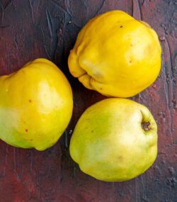 trei gutui delicioase pe masa, fundal închis la culoare