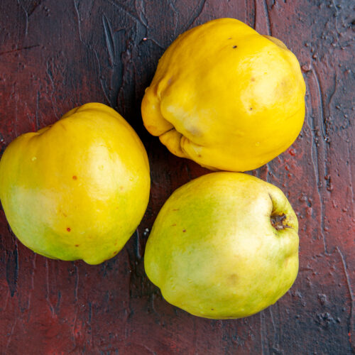 trei gutui delicioase pe masa, fundal închis la culoare