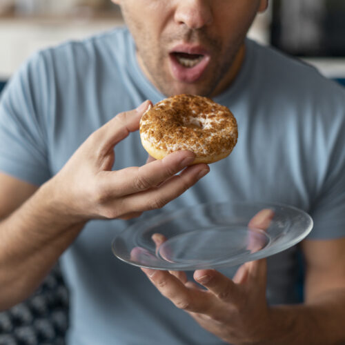 Imagine de aproape, bărbat care mănâncă o gogoașă