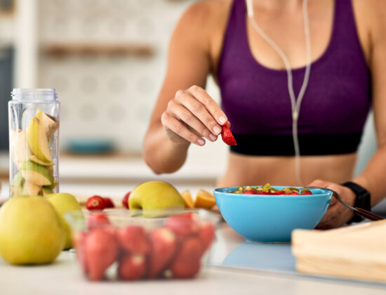 Imagine de aproape, se vede doar trunchiul unei femei îmbrăcată în echipament sport care își pregătește masa post-antrenament