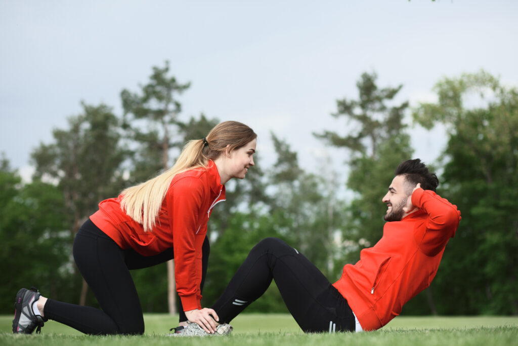 Cuplu de tineri îmbrăcați în echipament sport, fac excerciții în natură