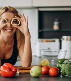tanara atletica in bucatarie cu mancare sanatoasa in jur, este vesela