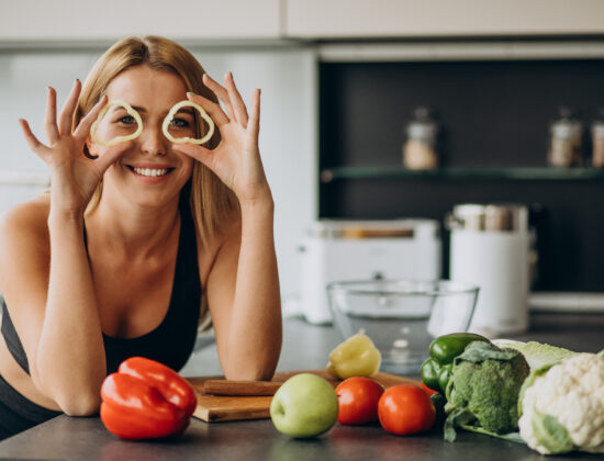 tanara atletica in bucatarie cu mancare sanatoasa in jur, este vesela