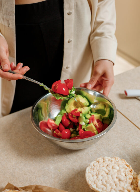 Imagine de aproape, persoană care pregătește o salată cu legume proaspete, preparat optim în dieta macrobiotică