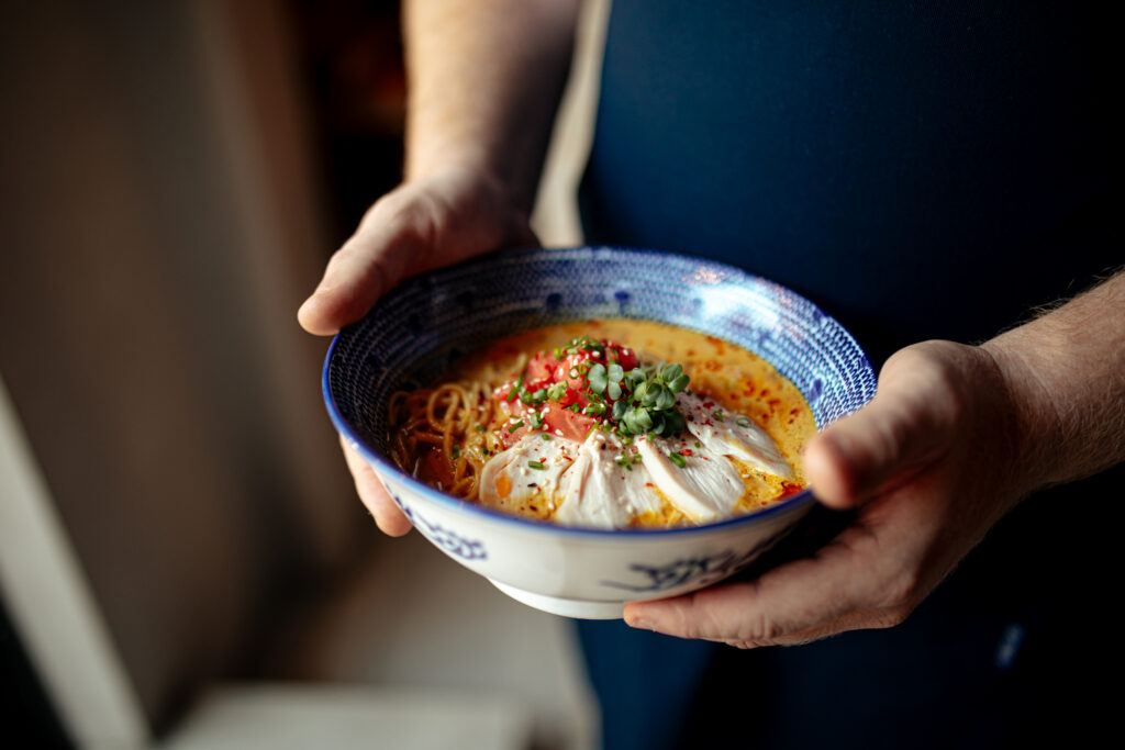 Imagine de aproape, bărbat care ține în mâini un bol de supă miso, optimă în dieta macrobiotică