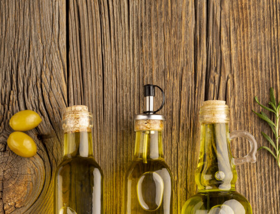 Sticluțe cu diferite tipuri de ulei d măsline întinse pe un fundal de lemn. Imagine de sus