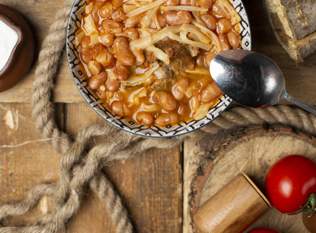 portie de fasole cu ciolan afumat intr-un bol, pe masa, cu vedere de sus