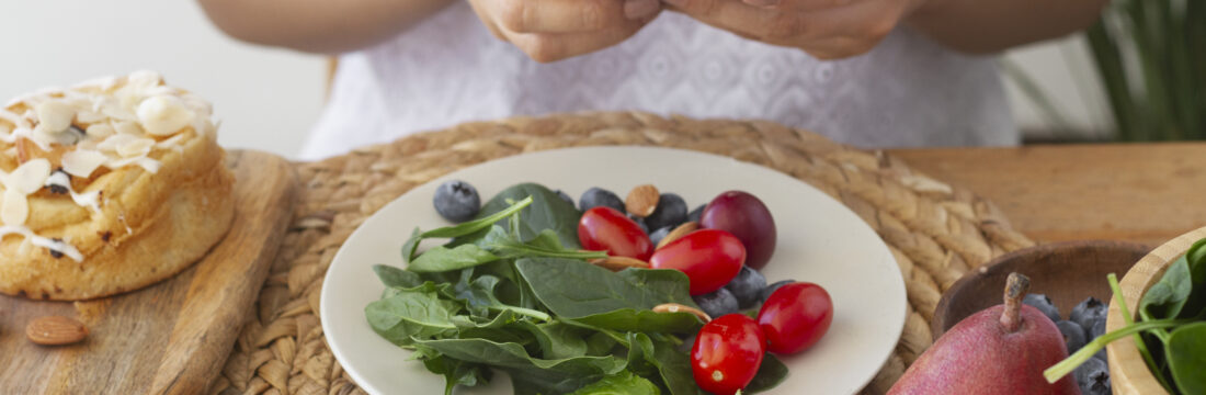 femeie sta la masa cu o salata sanatoasa in fata, tine in mana telefonul
