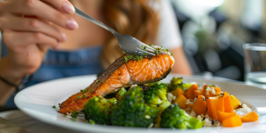 Imagine de aproape, persoană care înfige furculița într-o felie de somon la cuptor