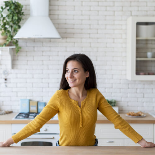 femeie in bucatarie fericita, multumita, zambeste