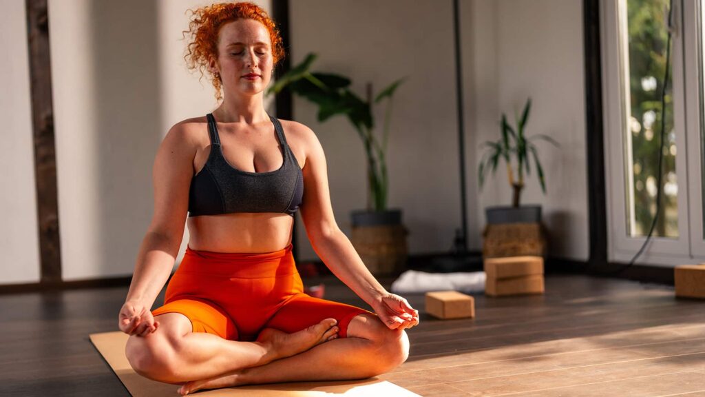 Persoană tânără roșcată face exercitii de yoga de respirație