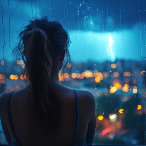 femeie se uita pe geam vreme ploioasa