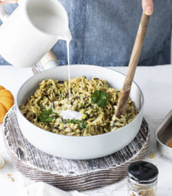 femeie care prepară paste orzo, toarna smântână lichidă