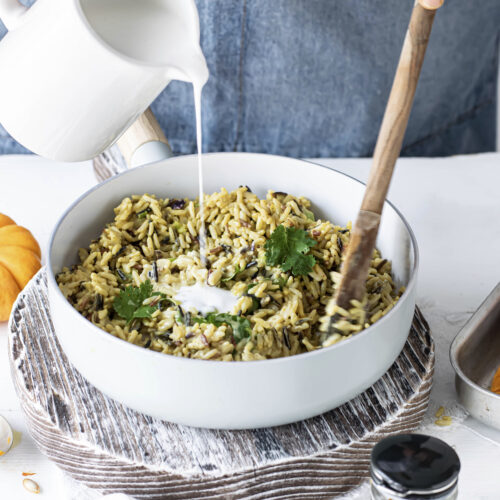 femeie care prepară paste orzo, toarna smântână lichidă